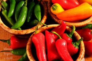 Captura de un surtido de Pimientos Dulces y Chiles en Tazones rociados con agua sobre una superficie de madera rústica.